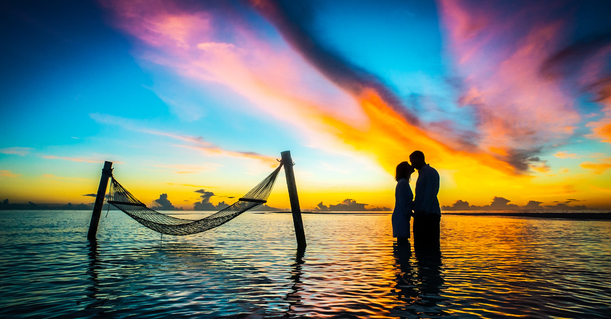 A silhouette of a man and a woman in a passionate embrace with vibrant energy beams emanating from their bodies, signifying the different types of energy in a relationship.