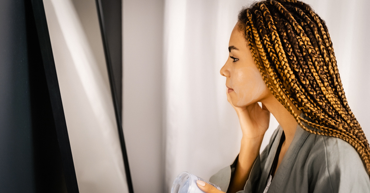 A woman looking at her reflection in the mirror, smiling confidently at herself.