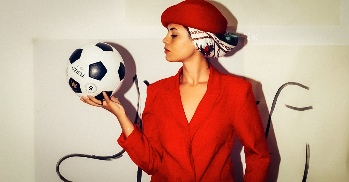 A single woman confidently standing alone, surrounded by light with a soccer ball